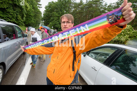 Ramstein-Miesenbach, Deutschland. 11. Juni 2016. Eine Friedensaktivistin lesen "Stopp Ramstein" während der Kampagne "Stopp-Ramstein" vor dem Eingang der US Air Force Base in Ramstein-Miesenbach, Deutschland, 11. Juni 2016 Banner hochhalten. Sie demonstriert gegen die US-amerikanischen Luftwaffenstützpunkt und seine Rolle in den Drohnenkrieg. Foto: OLIVER DIETZE/Dpa/Alamy Live News Stockfoto