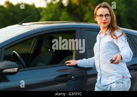 Junge Frau in der Nähe ein Auto mit Schlüssel in der Hand - Konzept für den Kauf eines Gebrauchtwagens oder einen Mietwagen Stockfoto