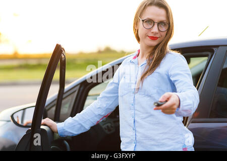 Junge Frau in der Nähe ein Auto mit Schlüssel in der Hand - Konzept für den Kauf eines Gebrauchtwagens oder einen Mietwagen Stockfoto