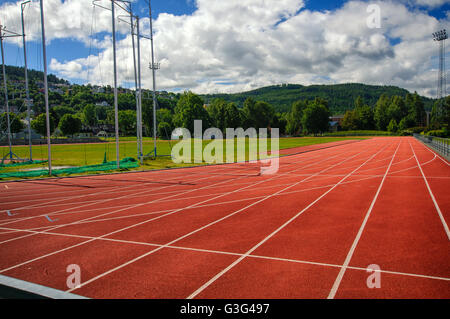 Laufstrecken im Stadion unter Bäumen und Bergen Stockfoto