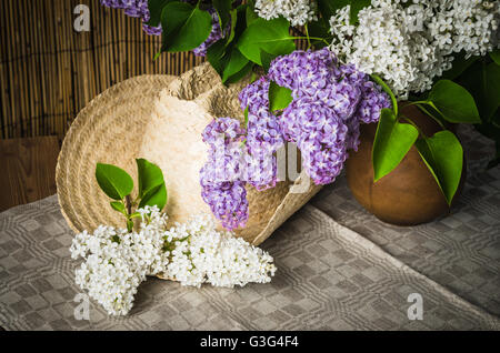 Stillleben mit einem Bouquet von Flieder und einen Strohhut, close-up Stockfoto