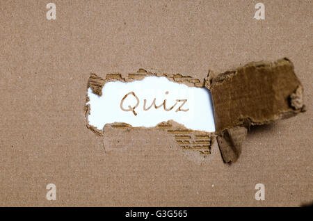 Das Wort Quiz erscheint hinter zerrissenes Papier. Stockfoto