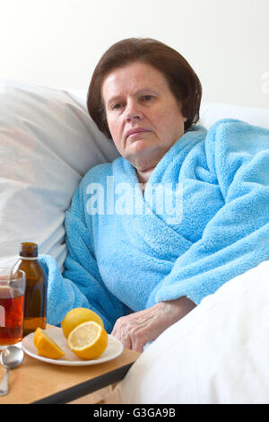 Kranke ältere Frau im Bett liegend Stockfoto