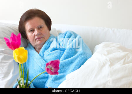 Kranke ältere Frau im Bett liegend Stockfoto