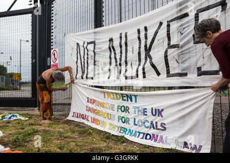 Burghfield, UK. 11. Juni 2016. Ex-Greenham Common Frieden Aktivisten hängen Banner auf der Umzäunung an AWE Burghfield am fünften Mal in Folge Tag einer Blockade des Eingangs Lieferungen im Rahmen eines Monats gegen Trident Erneuerung bestimmt "zu blockieren, zu besetzen und zu stören" montiert die Fabrik verantwortlich für die Endmontage der Trident Atomsprengköpfe. Bildnachweis: Mark Kerrison/Alamy Live-Nachrichten Stockfoto