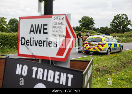 Burghfield, UK. 11. Juni 2016. Verteidigungsministerium Polizisten Debatte mit einer Friedens-Aktivistin, ob hängende aus der Umzäunung des AWE Burghfield Verstöße gegen die Satzung während einer Blockade der Lieferungen-Eingang auf der Website Banner. Bildnachweis: Mark Kerrison/Alamy Live-Nachrichten Stockfoto