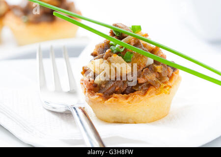 Törtchen mit Champignons und Gemüse auf einem weißen Teller Stockfoto