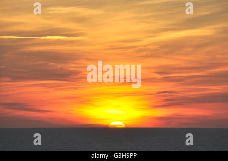 Cornwall - untergehende Sonne am Horizont versinkt - dunkle unruhigen Meer - Himmel gestreift, rot und Gold - dunkle Wolken Nacht fallen Stockfoto