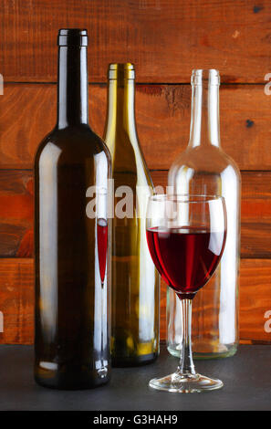 Drei leere Weinflaschen ein ein Glas in einem Keller Stockfoto