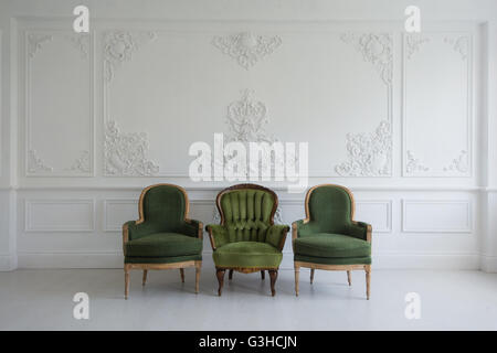 Set grün Vintage Holzstühle stehen vor einer weißen Wand Basrelief Stuck Zierleisten-Jahrgang Designelemente auf hellem Eichenparkett. Stockfoto