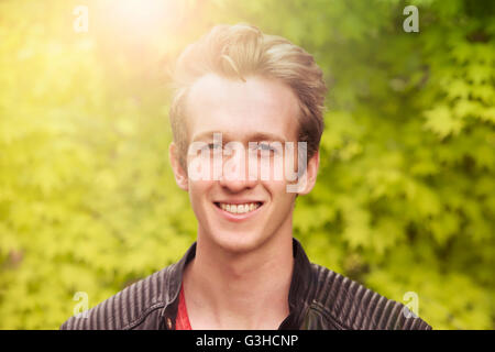 Porträt eines jungen blonden Mannes draußen und lächelt in die Kamera Stockfoto