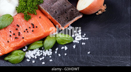 Bio King-Wildlachs Filet mit frischen Kräutern, Gewürzen und Gemüse auf schwarzen Steinplatte. Gesund kochen-Konzept. Stockfoto