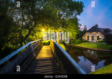Giethoorn, Niederlande. Brücke auf den Dorpsgracht oder Dorf Kanal mit umgebauten Bauernhaus auf der Insel mit eigenem Brücke. Stockfoto