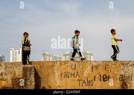 Jakarta, Indonesien. 18. April 2016. Kinder spielen am Flussufer wie Hochhäuser auf dem Hintergrund gesehen werden. © Garry Andrew Lotulung/Pacific Press/Alamy Live-Nachrichten Stockfoto