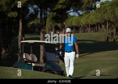 schöne orientalische Golfer Tragetasche und zu Fuß zum nächsten Loch am Golfplatz Stockfoto