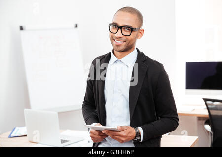 Porträt eines glücklich lächelnde Geschäftsmann hält Tablet pc im Büro stehen Stockfoto