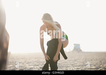 Junge Frau anziehen Neoprenanzug am Venice Beach, Kalifornien, USA Stockfoto