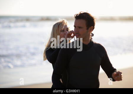 Junge Frau Reißverschluß Freunde Neoprenanzug am Venice Beach, Kalifornien, USA Stockfoto