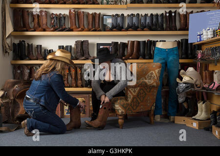 Shop Assistant hilft Kunden mit Stiefeln Stockfoto