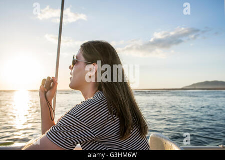 Junge Frau fotografieren Sonnenuntergang aus Mündung Ausflugsboot, Tamarindo, Guanacaste, Costa Rica Stockfoto