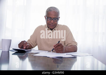Senior Mann sitzt am Tisch, Papierkram zu tun Stockfoto