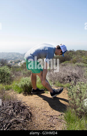 Mann am Berg tun Bein stretching-Übungen Stockfoto