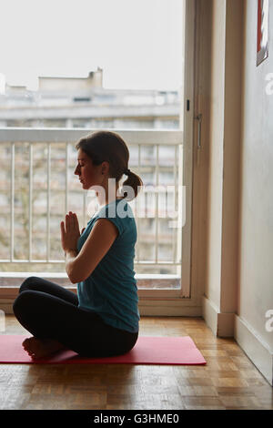 Seitenansicht der Frau sitzt Schneidersitz, Hände zusammen meditieren Stockfoto