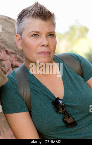 Kurze dunkelhaarige Frau lehnt sich an Felsen wegschauen Stockfoto