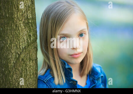 Porträt von blonde kurzhaarige Mädchen lehnte sich gegen Baum in Bluebell Wald, Hallerbos, Brüssel, Belgien Stockfoto