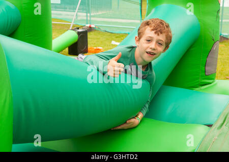 Sieben Jahre alter Junge auf eine Hüpfburg, Alresford Music Festival 2016 Alresford, Hampshire, England, Vereinigtes Königreich. Stockfoto