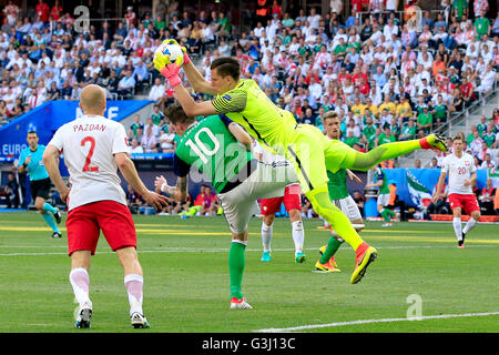 Northern Ireland Kyle Lafferty (Mitte) und Polen Torhüter Wojciech Szczesny (rechts) kollidieren, wie sie für den Ball während der UEFA Euro 2016, Gruppe C Spiel im Stade de Nizza, Nizza gehen. Stockfoto