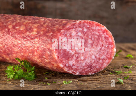 Frische italienische Salami auf Holzbrett mit Kräutern Stockfoto