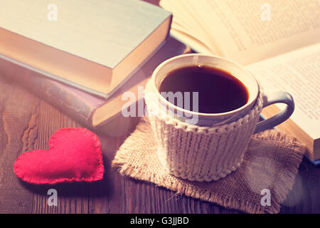 Tasse Kaffee und alte Bücher und ein Herz Stockfoto