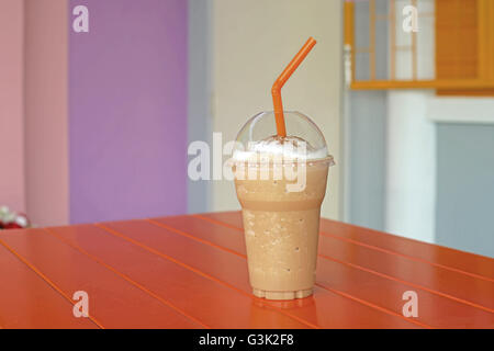 Eis-Kaffee-Smoothie auf orange Holztisch Stockfoto