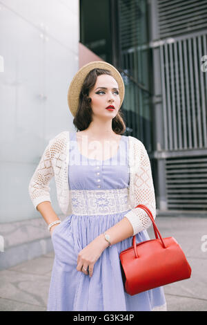 Porträt einer jungen Retro-Frau im blauen Kleid mit roten Tasche Stockfoto