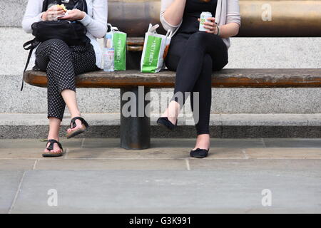 Zwei Frauen sitzen auf einer Bank am Trafalgar Square in London, England Stockfoto