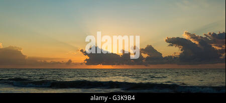 Die Sonne geht hinter Morgenwolken an einem Strand an der Ostküste von Australien Stockfoto