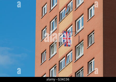 Ein Union Jack hängt aus einem Fenster in einem Wohnblock. Stockfoto