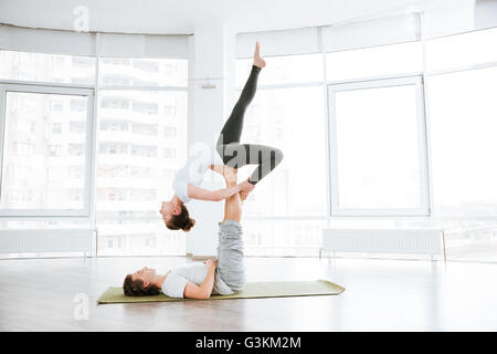 Entspannte junges Paar Acro Yoga im Studio zusammen üben Stockfoto