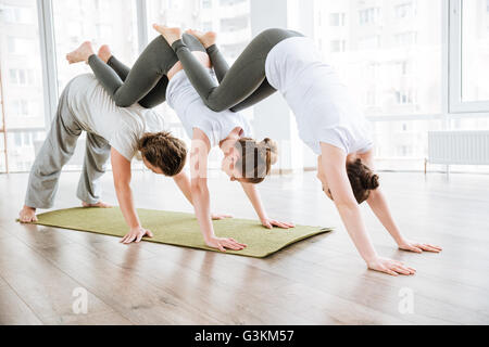 Mann und zwei Frauen üben Acro Yoga-Übungen in der Gruppe zusammen Stockfoto