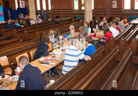 Regen bedeutete "The Big Lunch" im Inneren der Kirche zog. Bewohner in der Kirche, Essen Essen, Gemeinschaft Stockfoto