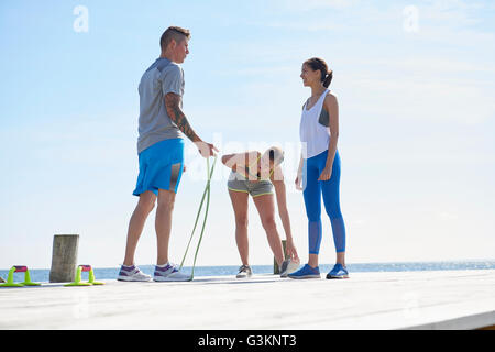 Freunde tragen Sportkleidung am Pier mit Springseil Stockfoto