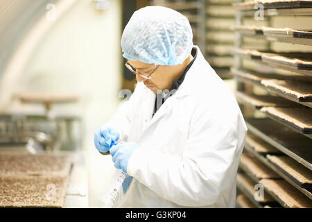 Seitenansicht des Arbeitnehmers trägt Haarnetz und Latex Handschuhe sammeln von Proben in Plastiktüte Stockfoto