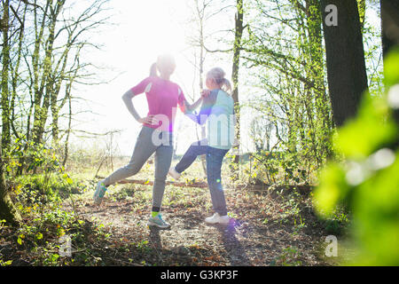 Frauen im Wald von Angesicht zu Angesicht Beine angehoben dehnen Stockfoto