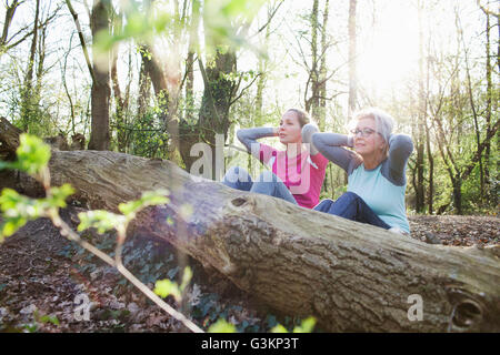 Frauen im Wald Hände hinter Kopf tun Sit up gegen umgestürzten Baum Stockfoto