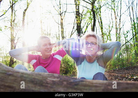 Frauen im Wald Hände hinter Kopf tun Sit up gegen umgestürzten Baum Stockfoto