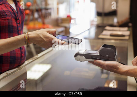 Ansicht der Womans Hände mit Smartphone für die kontaktlose Zahlung auf Smartphone zugeschnitten Stockfoto