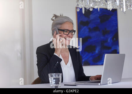 Frau mit Laptop, Telefon Anruf auf smartphone Stockfoto