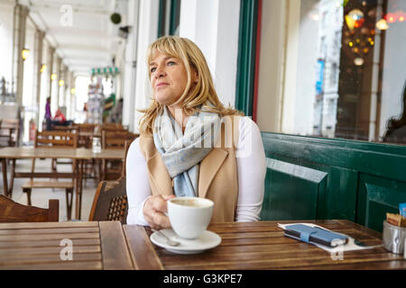 Reife Frau mit Blick vom Bürgersteig Café-Tisch Stockfoto