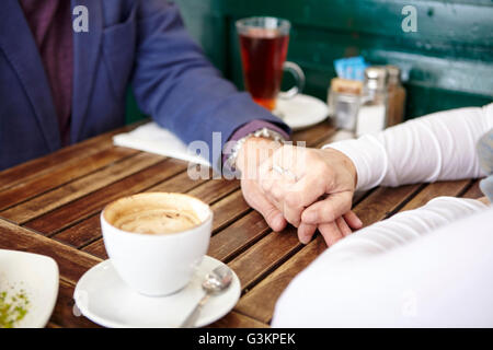 Nahaufnahme von Reife dating paar Hand in Hand am Bürgersteig Café-Tisch Stockfoto
